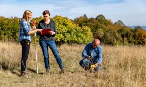 A land surveyor team marking property corners during a boundary survey in a Colorado field.