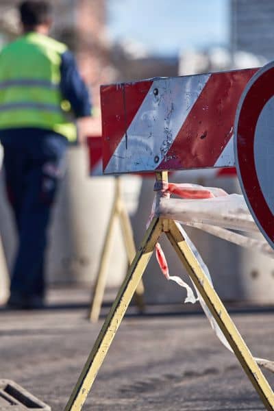 Roadwork scene with barriers and worker in safety vest showing the role of construction staking surveys in public infrastructure projects
