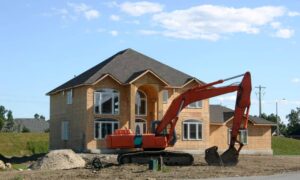 Excavator working near a home under construction, showing how site changes can affect drainage and may require a topographic survey