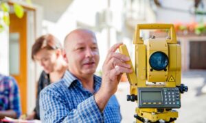 Surveyor using a total station to take measurements for a property survey in a residential neighborhood
