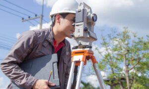 Land surveyor measuring property boundaries while determining the average cost for a land survey