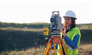 topographic survey colorado elevation check - ALTA SURVEY Colorado Land surveyor conducting a topographic survey with a total station on a grassy site, gathering elevation data for grading and drainage design.