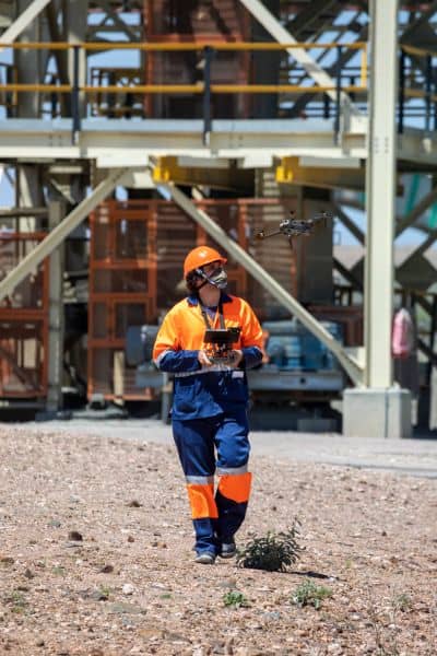 Drone surveying at a construction site with a surveyor in safety gear operating equipment to ensure accuracy during geomagnetic storms