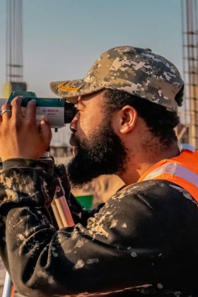 Surveyor using equipment at a construction site during daytime construction work

