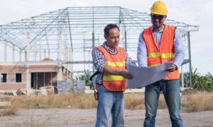 Engineers reviewing site plans before construction - ALTA SURVEY Colorado Licensed engineers reviewing construction plans together on a construction site to help prevent costly building mistakes