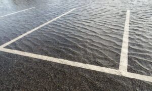 Standing water in a small commercial parking lot caused by poor drainage design
