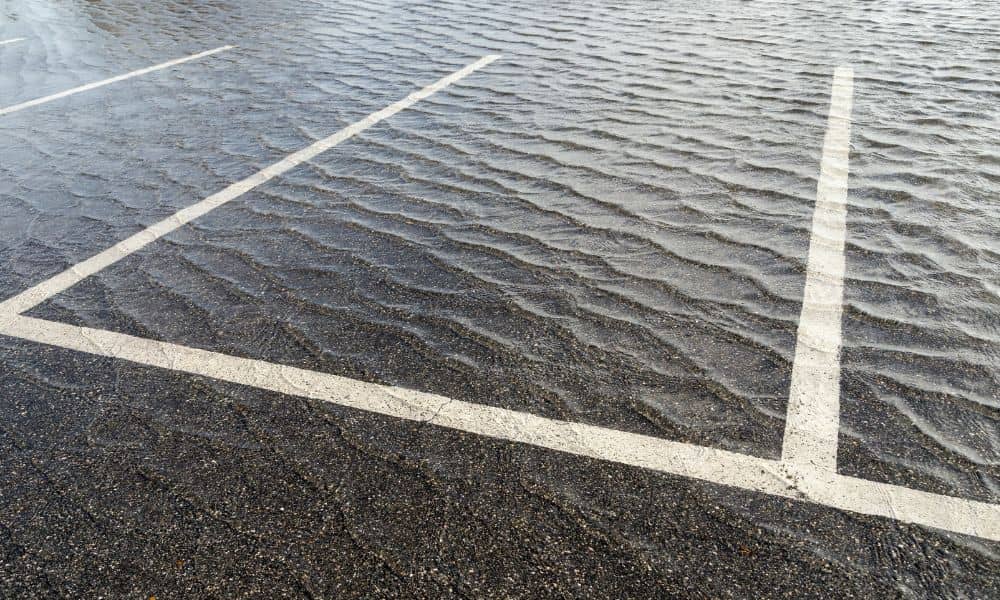 Standing water in a small commercial parking lot caused by poor drainage design