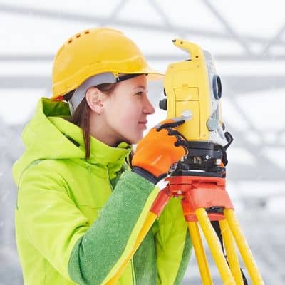 Surveyor measuring ground elevation winter conditions - ALTA SURVEY Colorado Land surveyor measuring ground elevation in winter conditions to analyze drainage patterns during a topographic survey