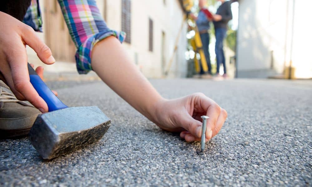 Licensed land surveyor setting a boundary marker nail on a property line