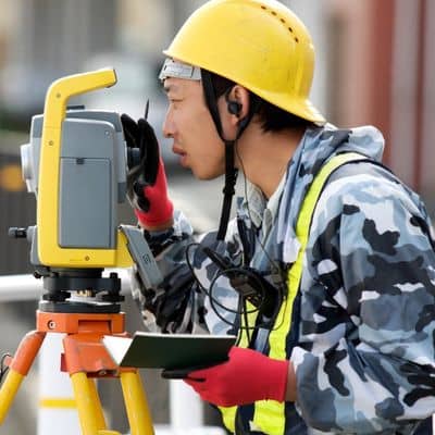 Surveyor using a total station to measure and verify property boundaries