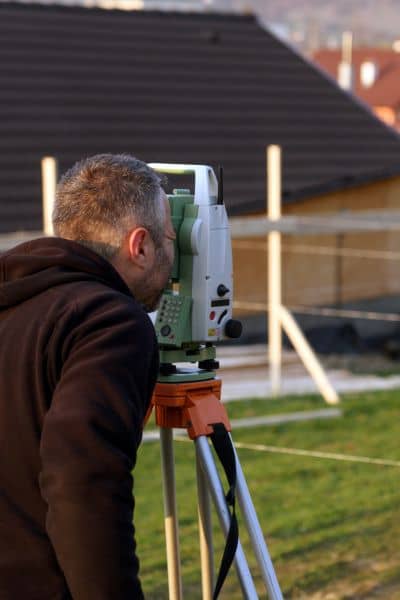 Residential land surveyor measuring property boundaries - ALTA SURVEY Colorado Land surveyor measuring property boundaries in a residential area to ensure accurate shed placement and boundary alignment
