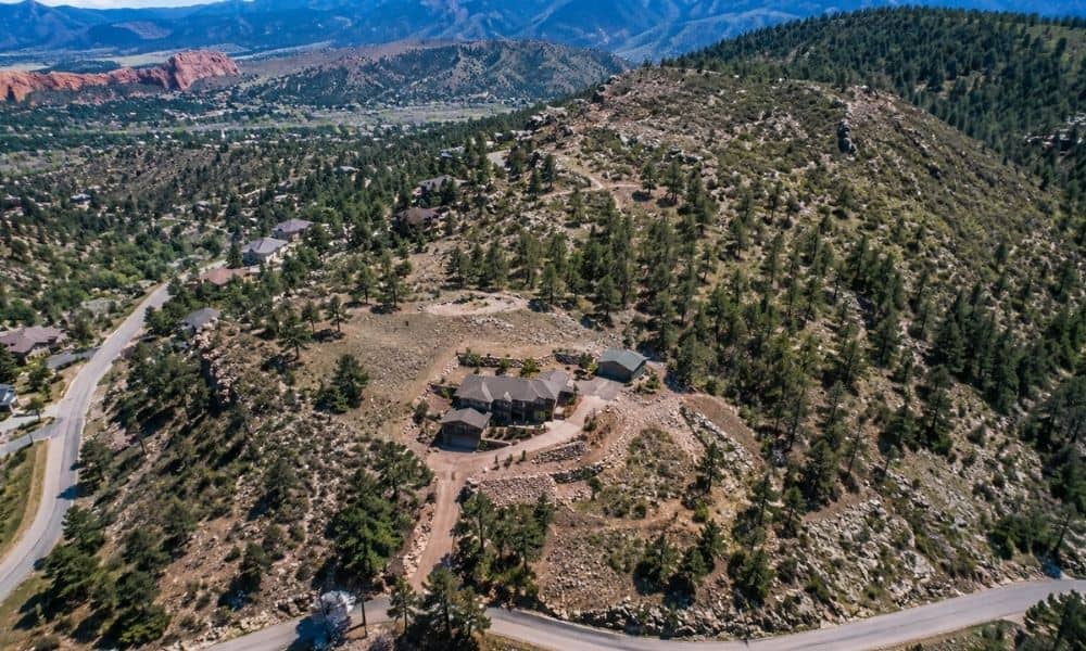 Aerial view of steep foothill terrain, rocky slopes, trees, and residential properties in Colorado Springs, CO, showing a landscape suited for drone surveying
